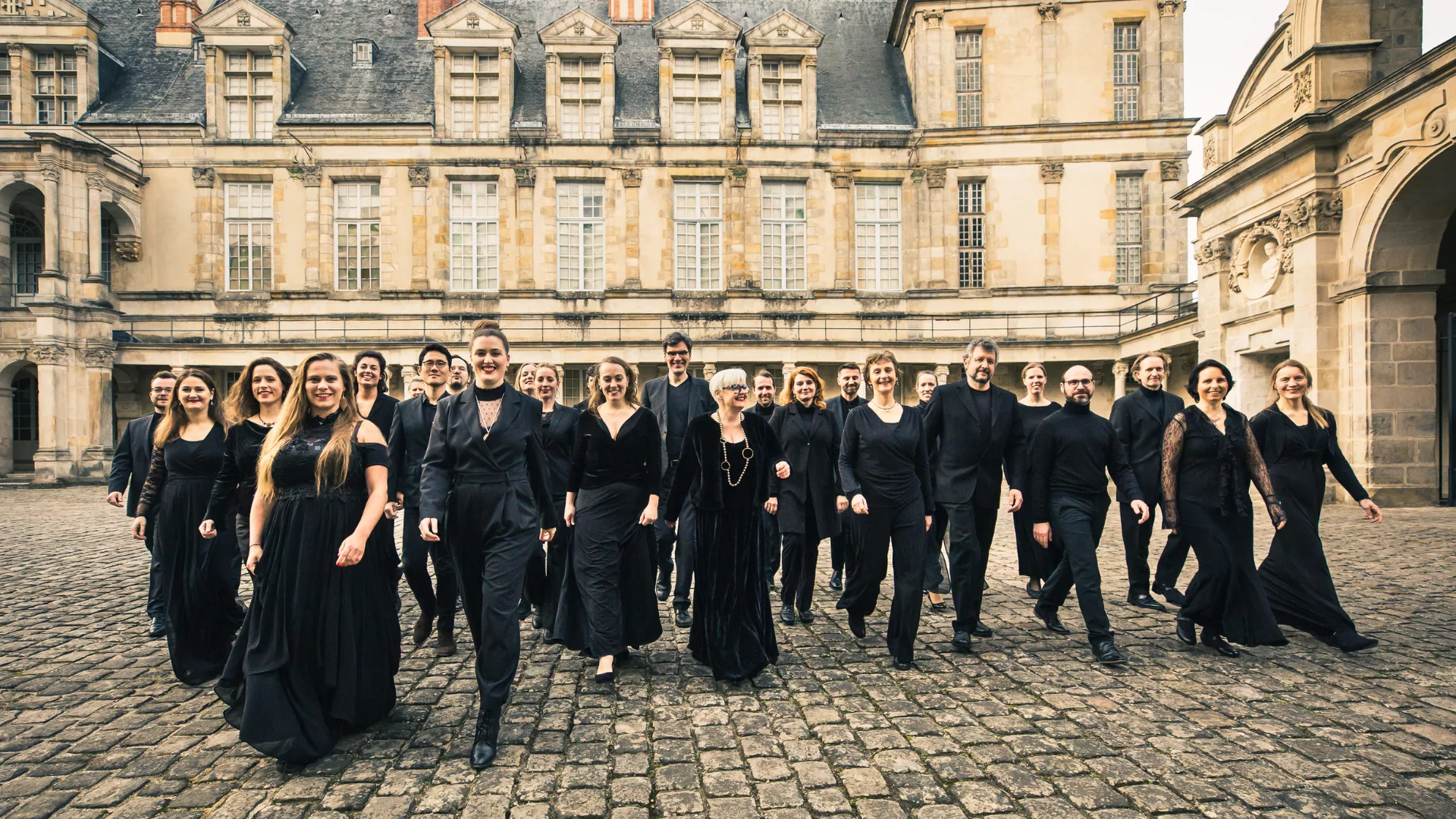 Foto dei componenti del Balthasar-Neumann-Chor che camminano nel cortile di un palazzo